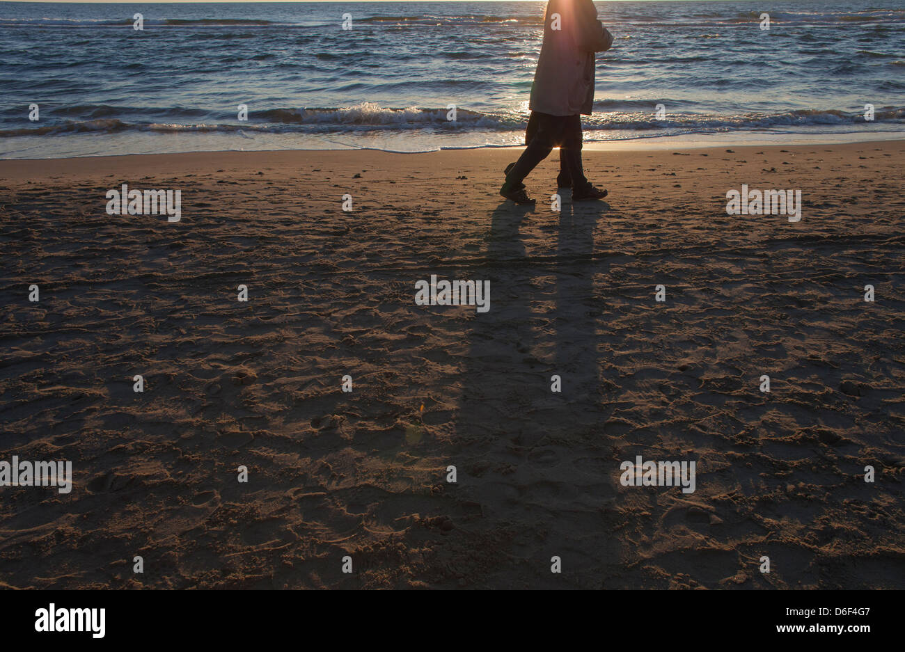 Quelqu'un marche au coucher du soleil sur la mer en hiver Banque D'Images