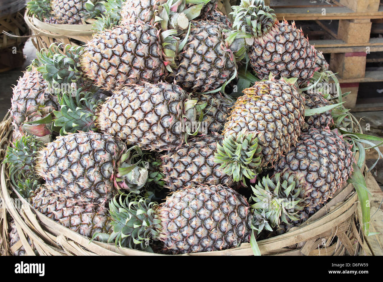 L'Ananas entassés dans le panier au marché de fruits et légumes en Asie du Sud-Est avec éclairage naturel Banque D'Images