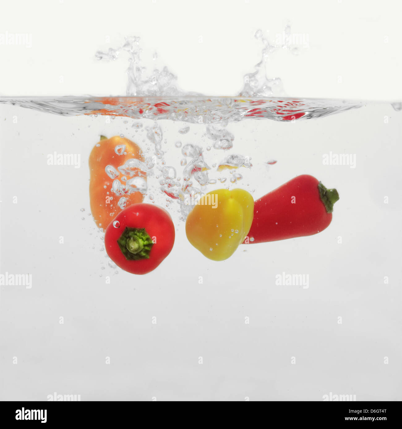 Piments multicolores aux éclaboussures dans l'eau Banque D'Images