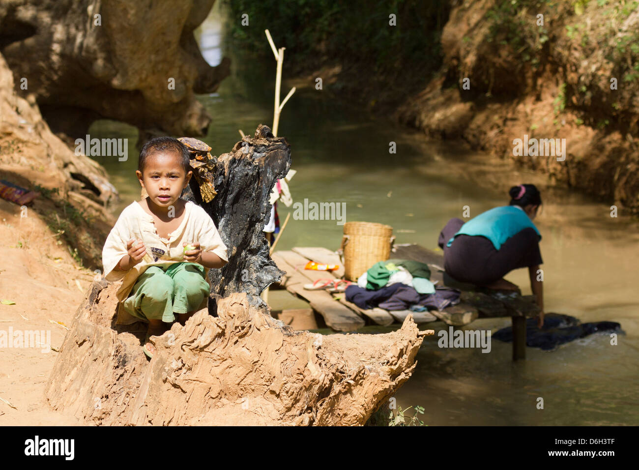 Jeune garçon par un ruisseau alors que sa mère ne la lave - Inn Thein Village 1 Banque D'Images