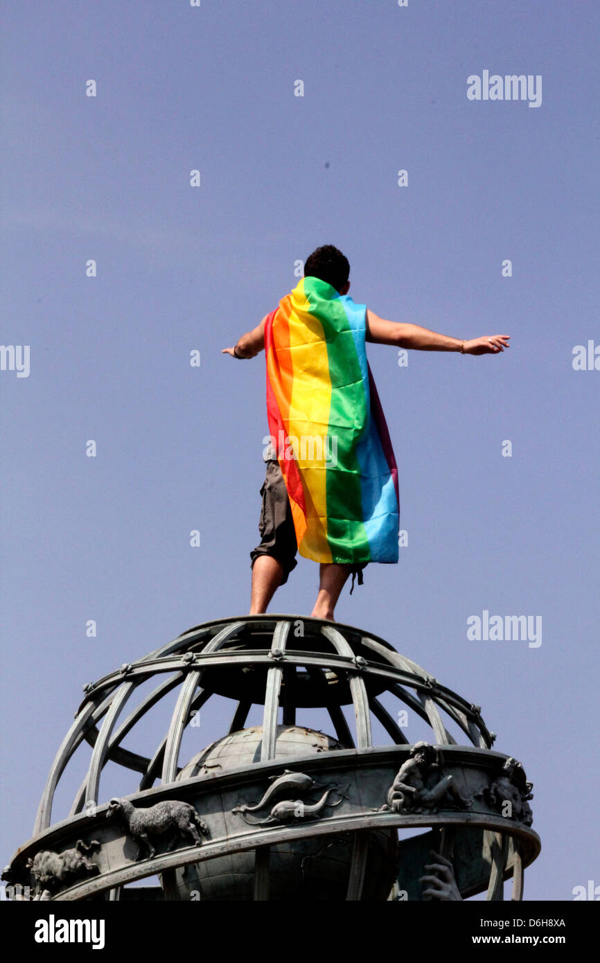 Paris gay pride. L'homme enveloppé dans le drapeau arc-en-ciel est debout sur le sommet de la planète statue dans le jardin du Luxembourg, Paris, France Banque D'Images