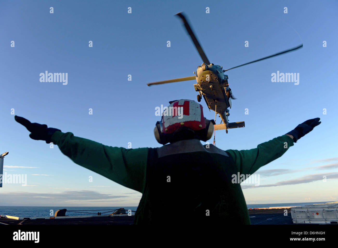 Un marin de l'US Navy dirige un Knight Hawk MH-60S pour supprimer un chargement sur le poste de pilotage à bord du porte-avions USS John C. Stennis, 19 mai 2013 dans la mer d'Oman. Banque D'Images