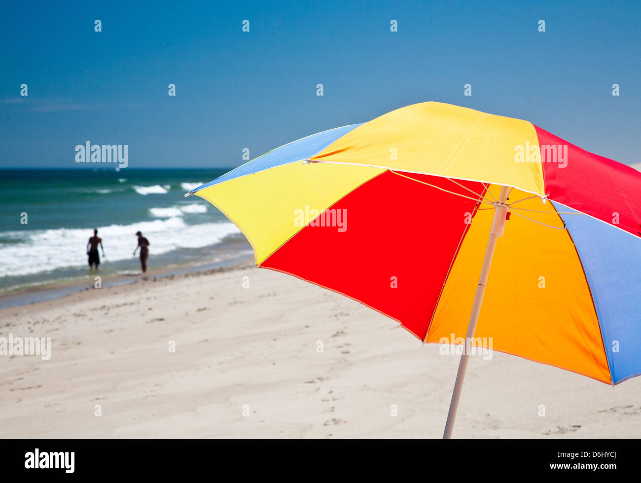 Parasol coloré dans le premier plan avec couple en jouant à distance dans l'océan Banque D'Images