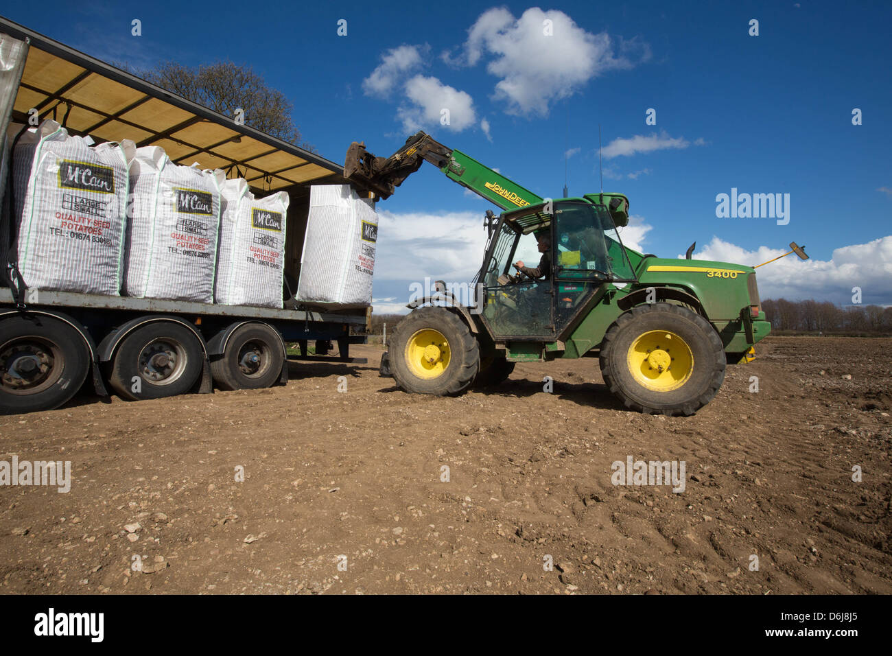 Télé John Deere handler le déchargement des sacs de pommes de terre de semence de l'écossais d'un camion Banque D'Images