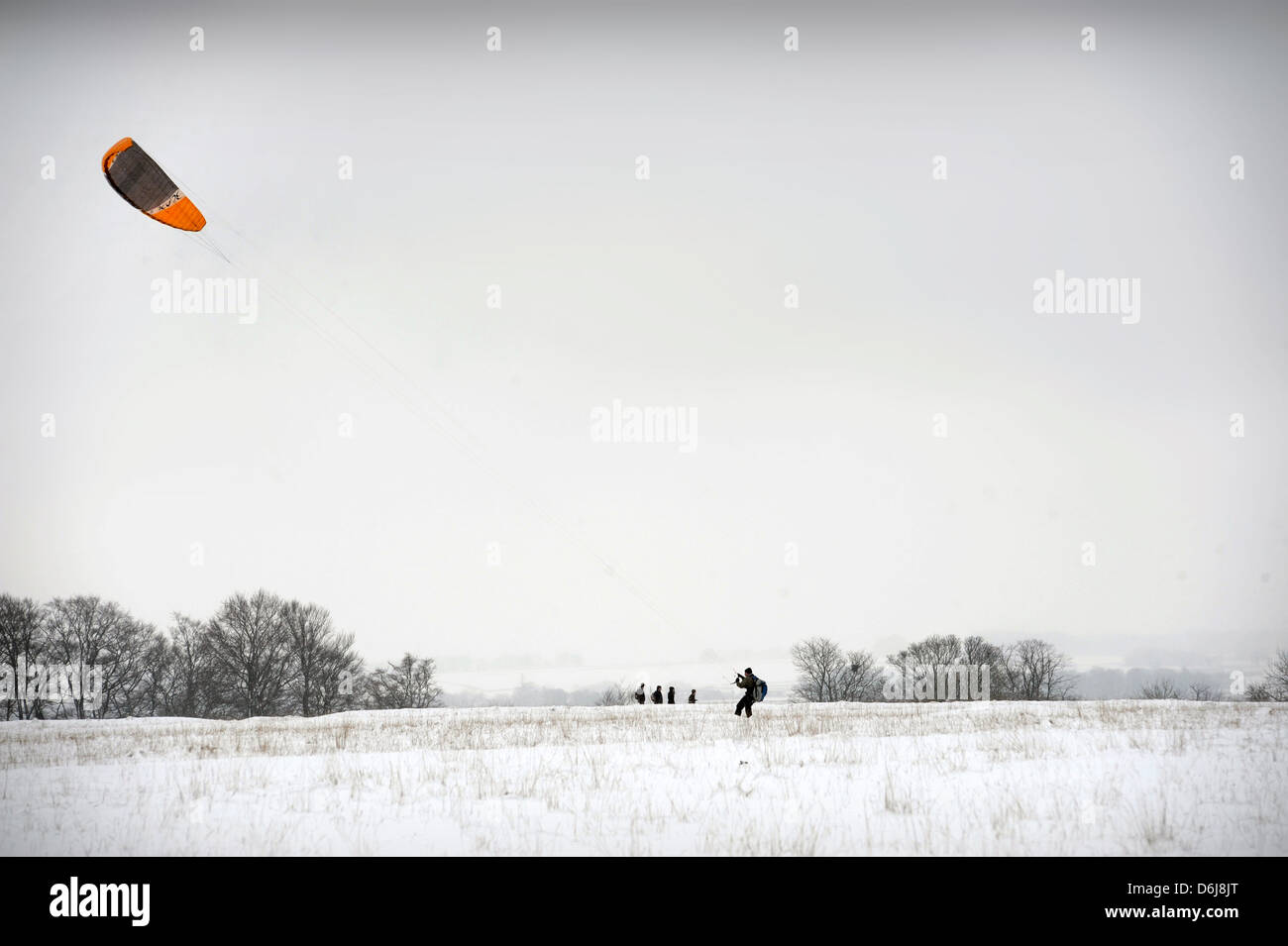 Un homme 'kitesurf' ou 'nowkiting' dans la neige sur Minchinhampton Common, Gloucestershire UK Banque D'Images