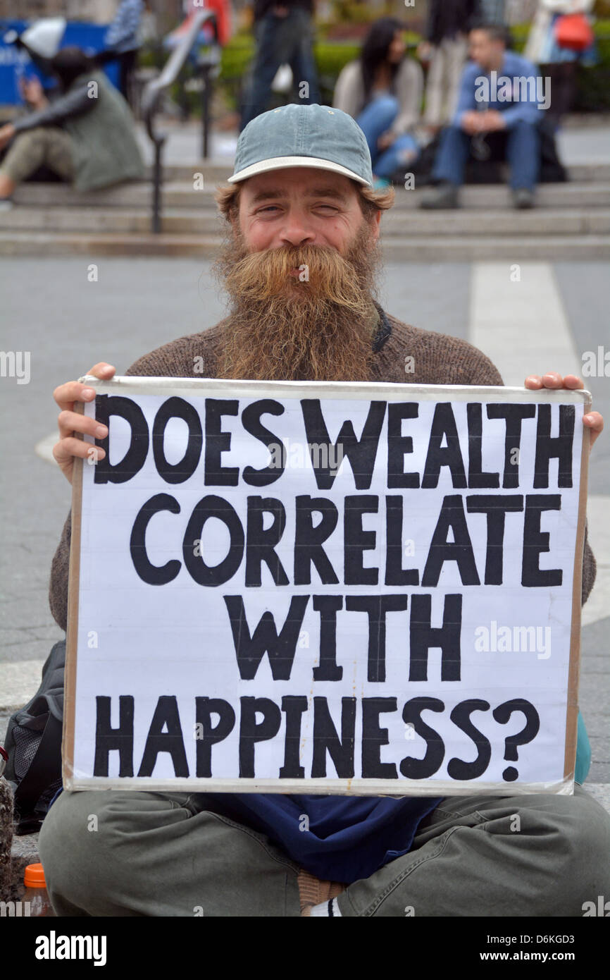 Homme avec un signe à Union Square Park de demander "la richesse en corrélation avec le bonheur ?' Banque D'Images