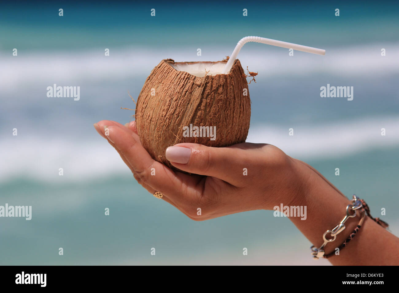 La noix de coco dans a woman's hand isolé sur fond de la mer Banque D'Images