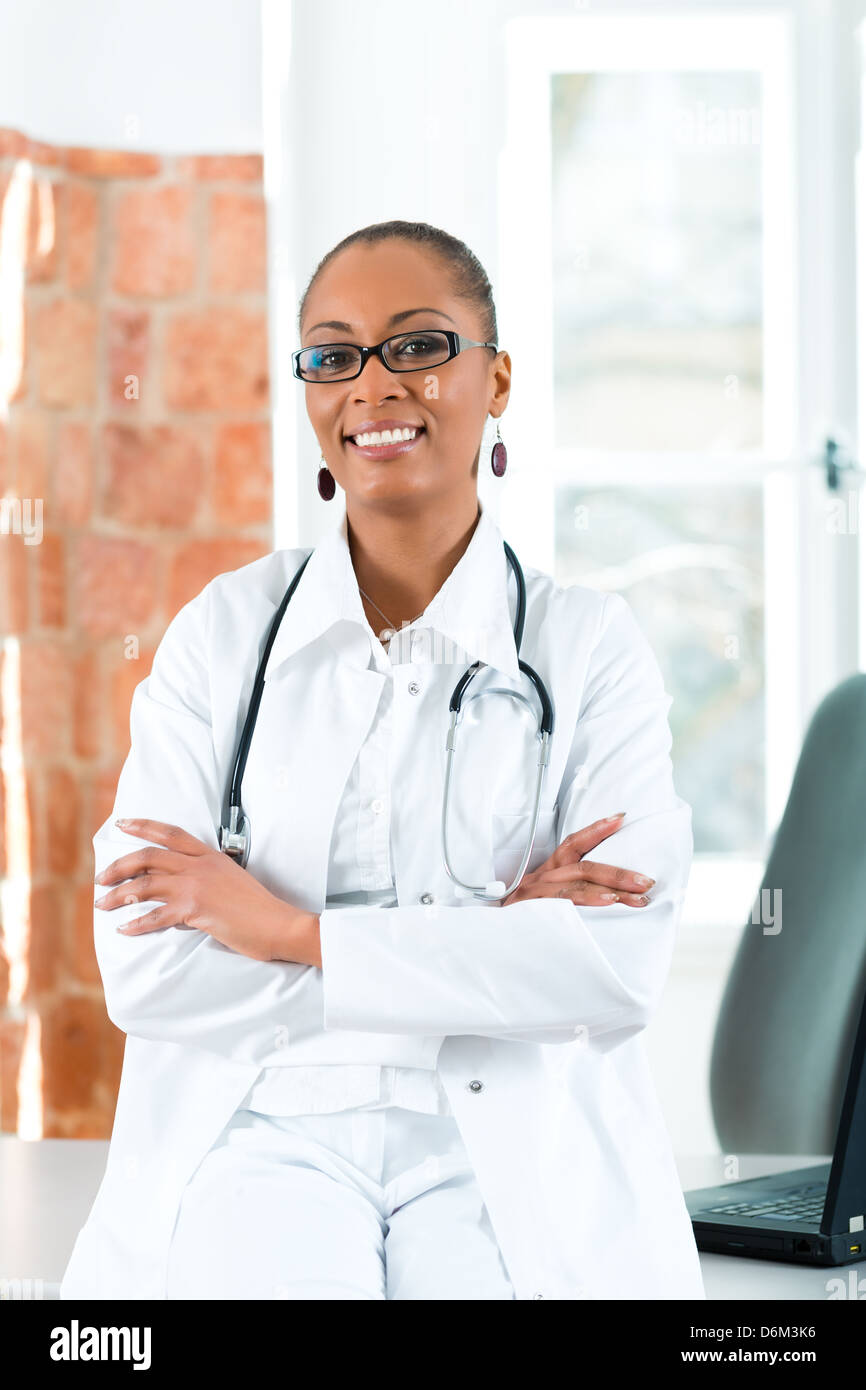 Jeune femme médecin noir debout à une fenêtre en clinique avec un fichier ou dossier Banque D'Images Jeune femme médecin noir debout à une fenêtre en clinique avec un fichier ou dossier Banque D'Images