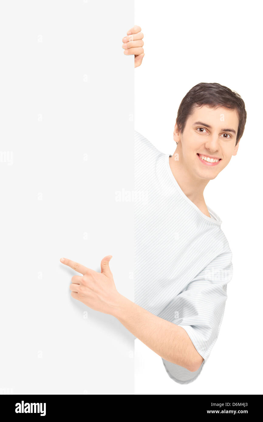 Young male patient dans une chemise d'hôpital en montrant un panneau vierge, isolé sur fond blanc Banque D'Images