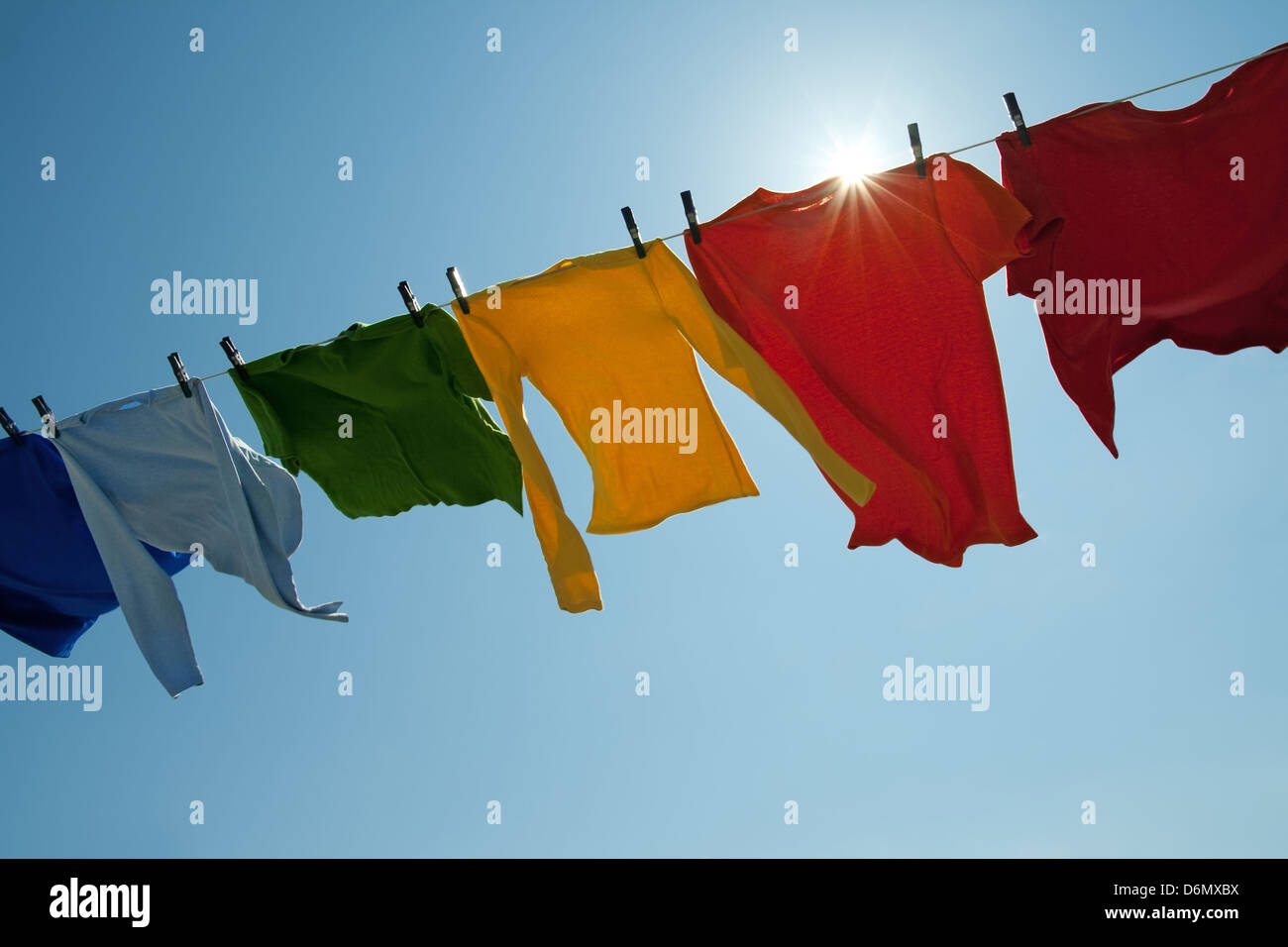 Soleil qui brille sur un fil à linge avec des vêtements sur un jour de vent. Banque D'Images