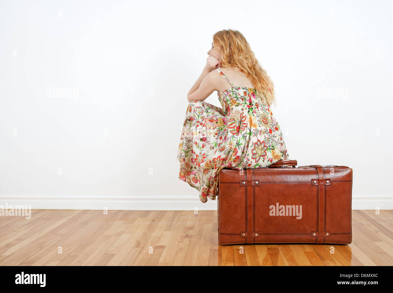Girl wearing robe d'été est assis sur une valise vintage, d'anticiper et de voyage en attente. Banque D'Images