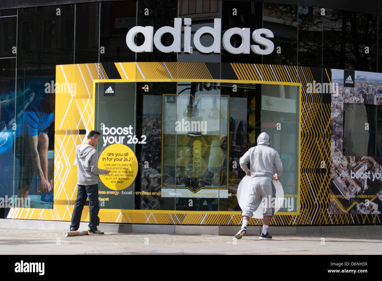 Magasin Adidas d'Oxford Street London, employé de magasin colle à  l'extérieur du shop logo Photo Stock - Alamy