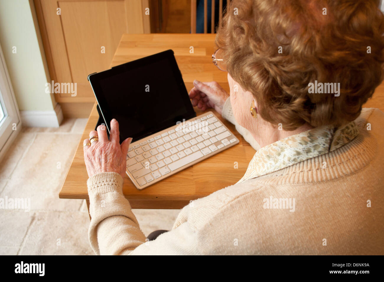 Femme âgée utilise un ordinateur tablette avec clavier sans fil Banque D'Images
