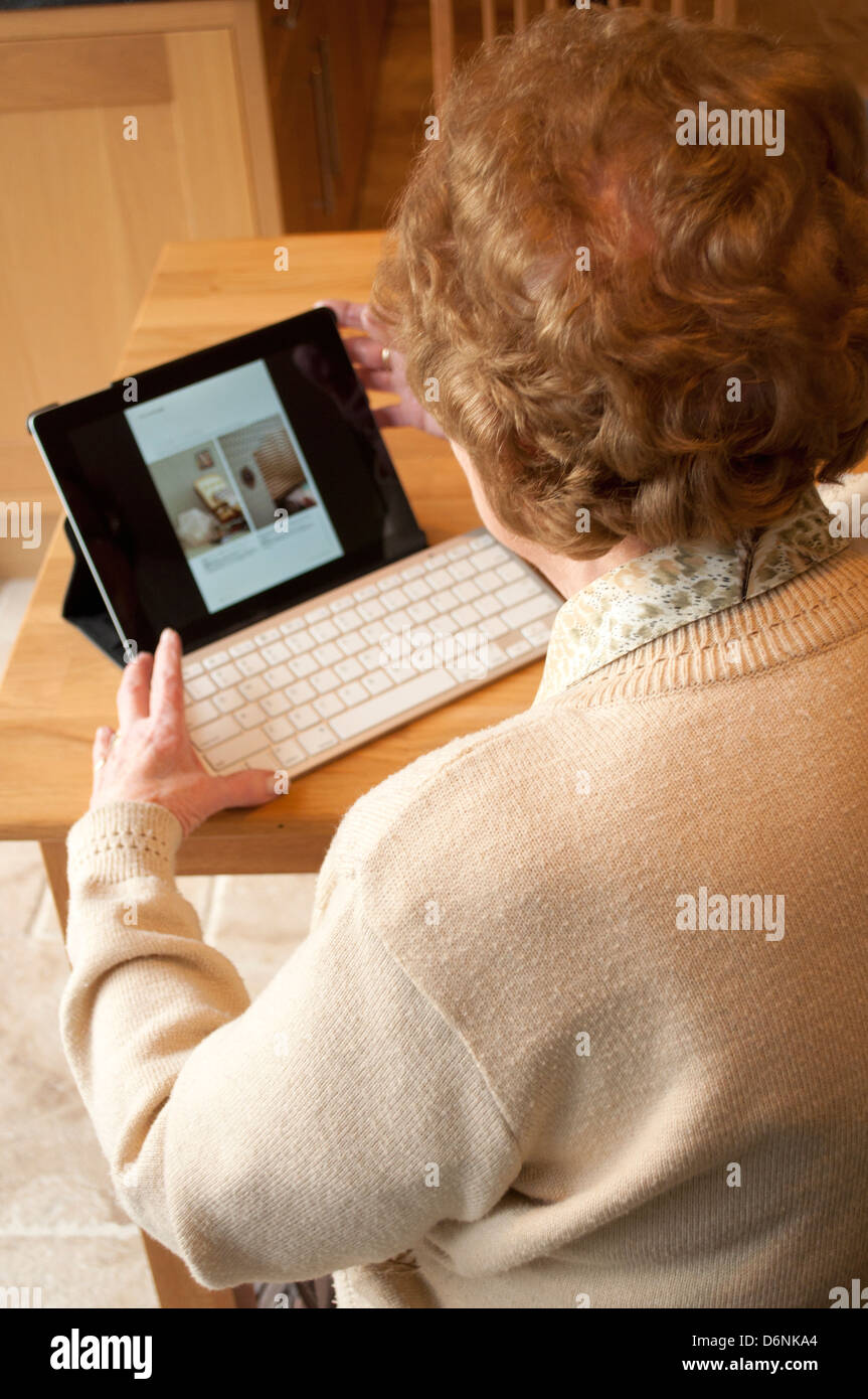 Femme âgée utilise un ordinateur tablette avec clavier sans fil Banque D'Images