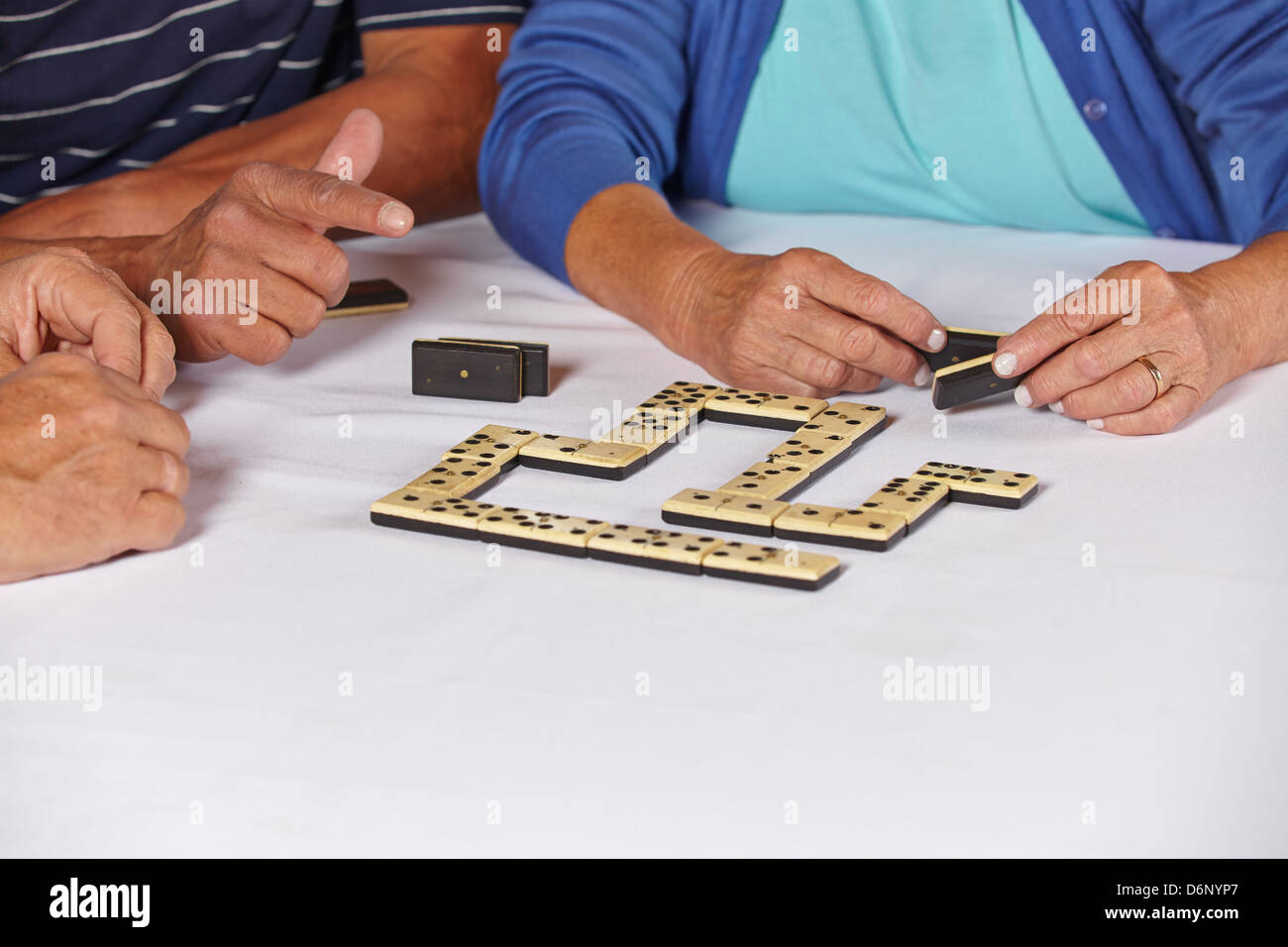 Mains de trois vieux aînés jouant un jeu de domino Banque D'Images