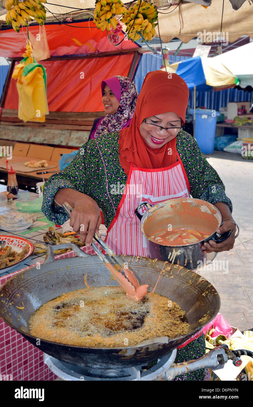 Les Malaisiennes faire frire les légumes dans la graisse chaude marché à l'Etat de Terengganu, Malaisie Banque D'Images