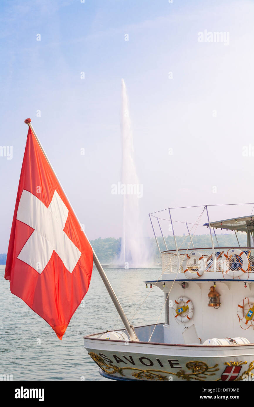 Drapeau national suisse sur un bateau à vapeur du lac de Genève, Suisse avec la fontaine du Jet d'eau sur le lac de Genève (Lac Léman) et ciel bleu Banque D'Images