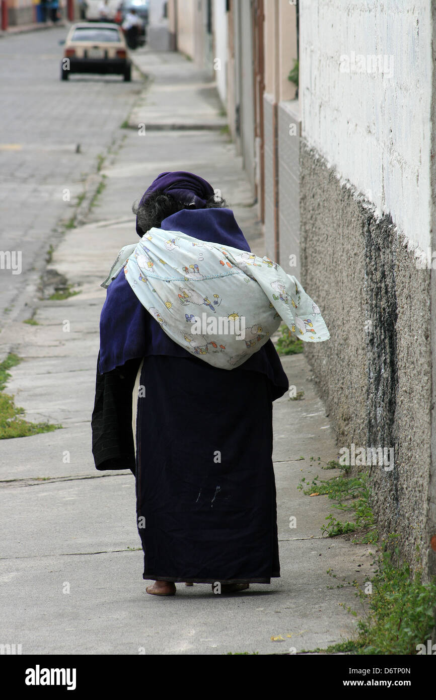 Une femme sans-abri autochtones transportant un sac marchant dans une rue à Cotacachi (Équateur) Banque D'Images