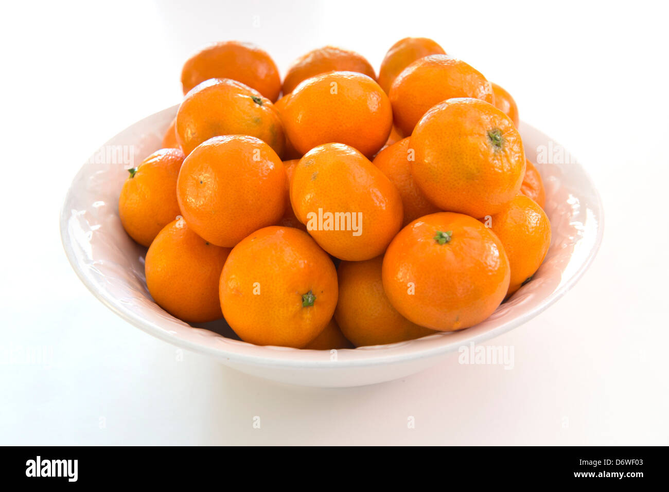 Oranges, clémentines une variété de mandarine, Citrus reticulata, dans un bol blanc, fond blanc. Banque D'Images