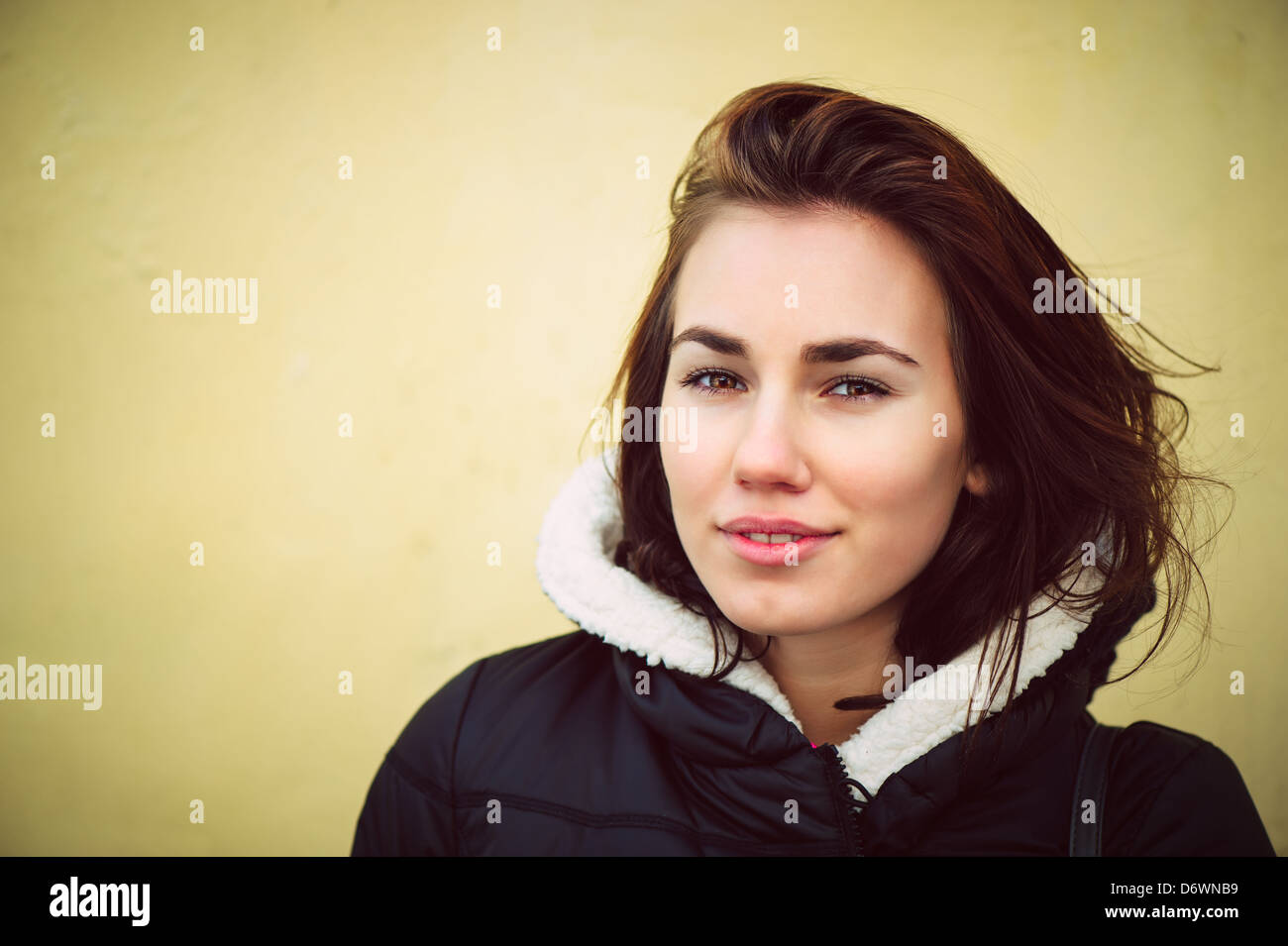 Femme brunette en modèle de mode veste noire en face de mur jaune Banque D'Images