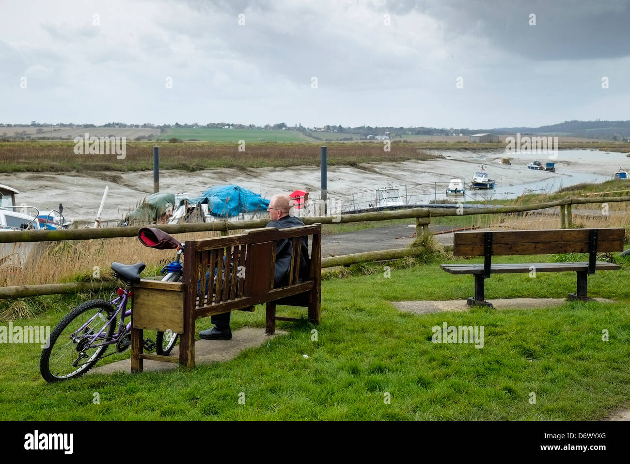 Un homme assis sur un banc avec vue sur Vange Creek. Banque D'Images