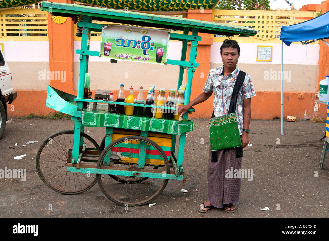 Homme birman se trouve à côté de son panier vendant des boissons sur une rue de Yangon Myanmar Birmanie Banque D'Images