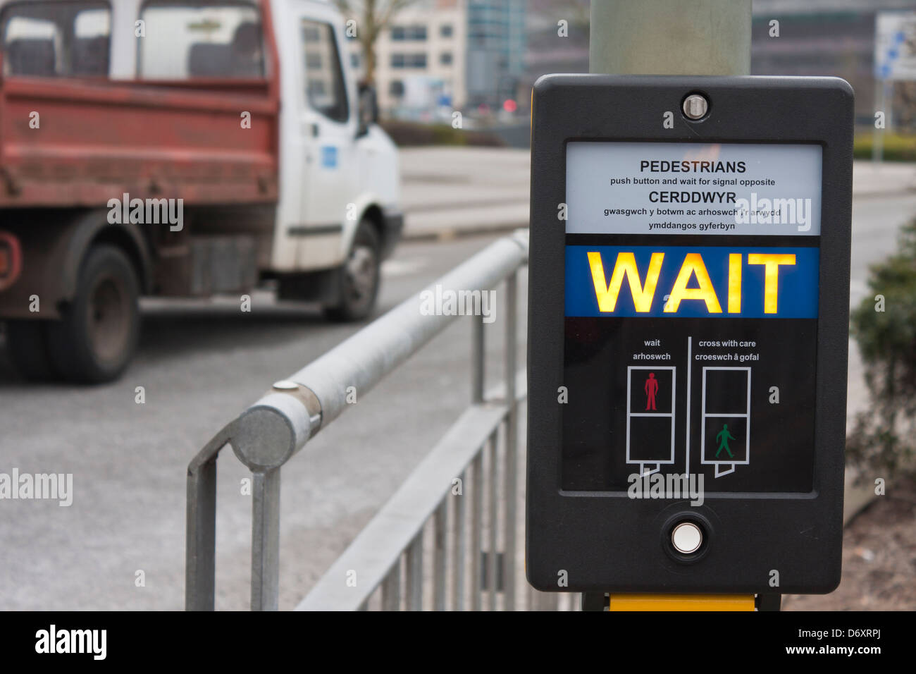 Signe d'attente des piétons à Pelican crossing en anglais et gallois. Banque D'Images