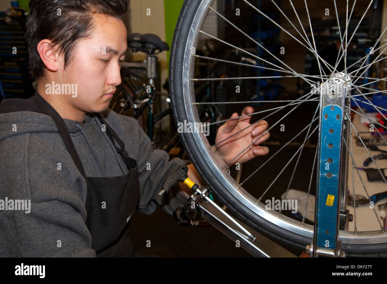 Adolescent asiatique l'alignement de roue de bicyclette dans le but non lucratif Youth Express Atelier de réparation de vélo. St Paul Minnesota MN USA Banque D'Images
