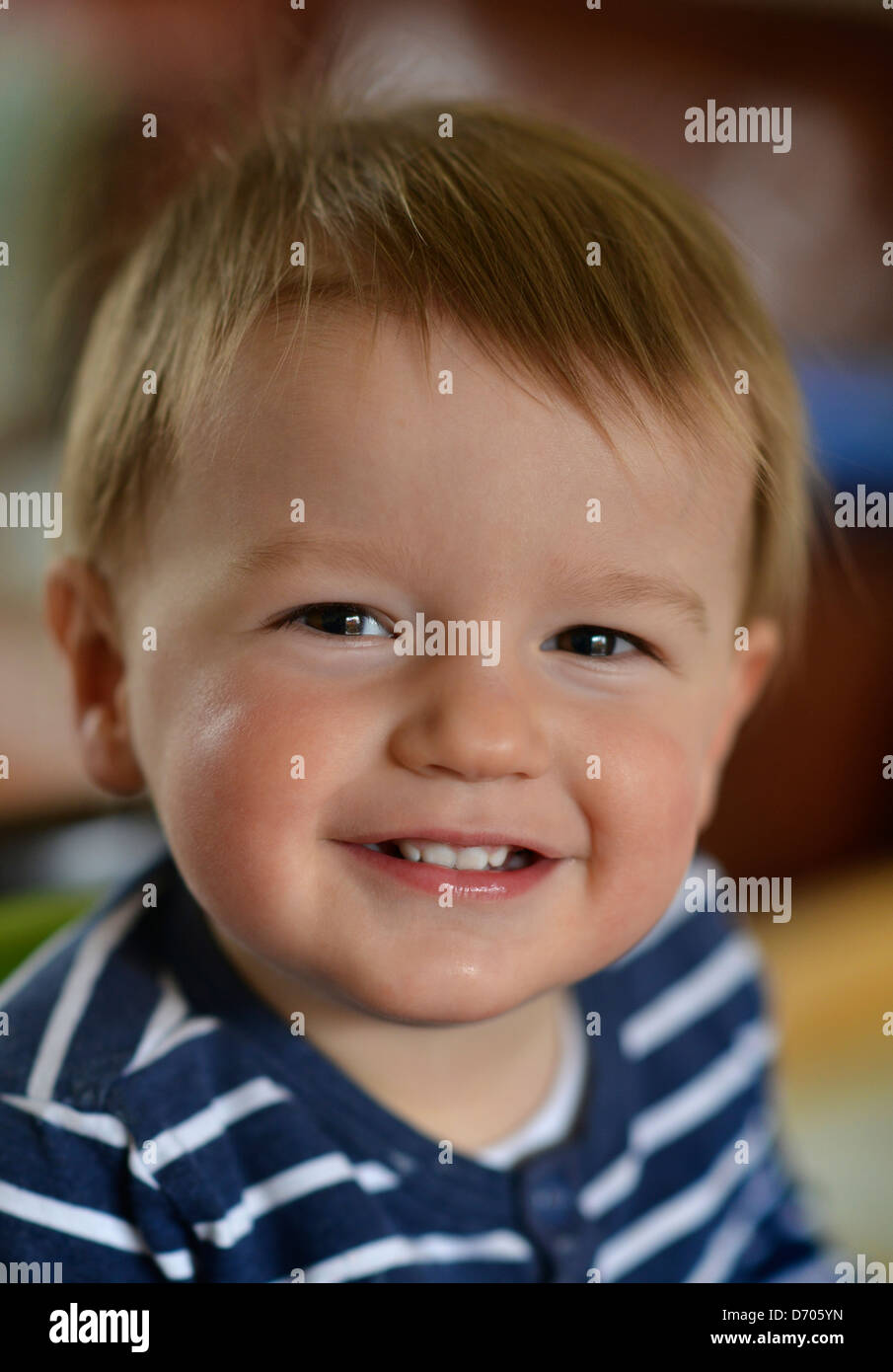 Une photographie de sourire tout-petit âgés de dix-huit mois, avec les cheveux bruns portant un déshabillé bleu et blanc t shirt. Banque D'Images