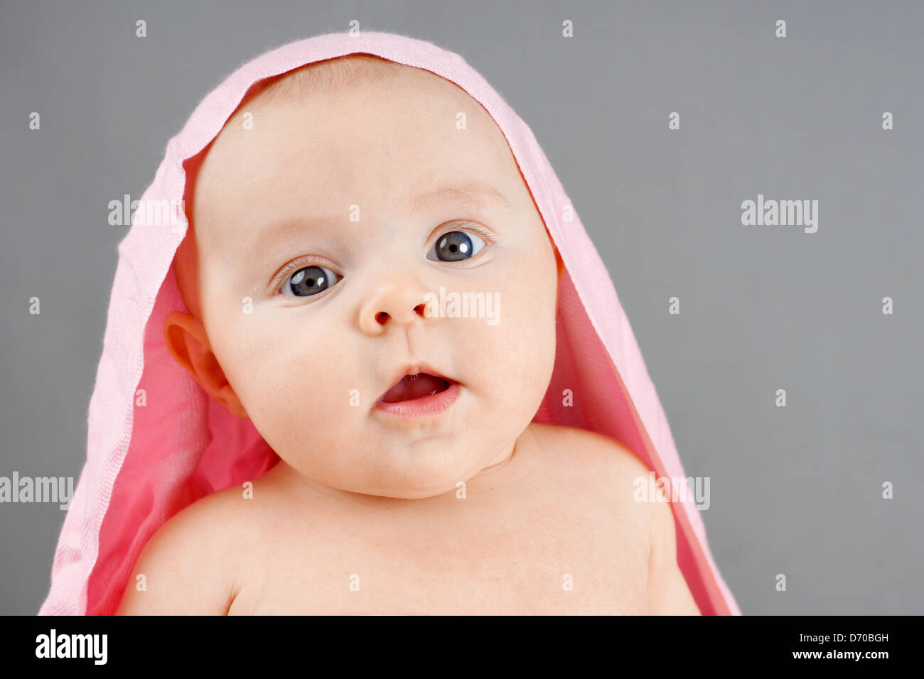 Portrait d'un surpris Naissance bebe Fille avec couverture rose sur la tête. Banque D'Images