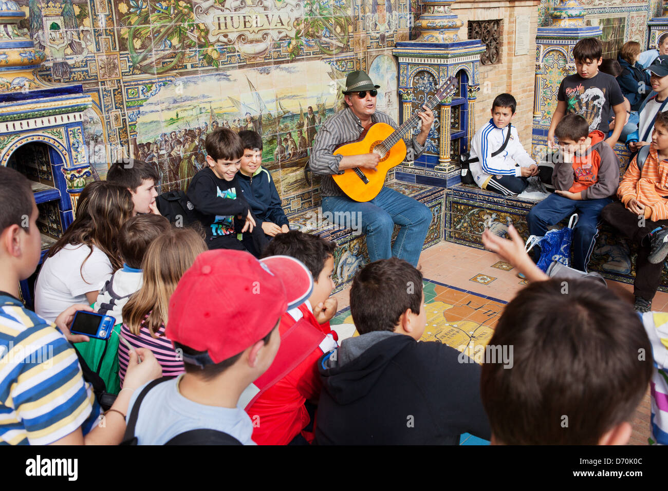 Musicien ambulant joue de la guitare, groupe d'enfants des écoles à l'écoute, Plaza de España à Séville, Espagne. Banque D'Images