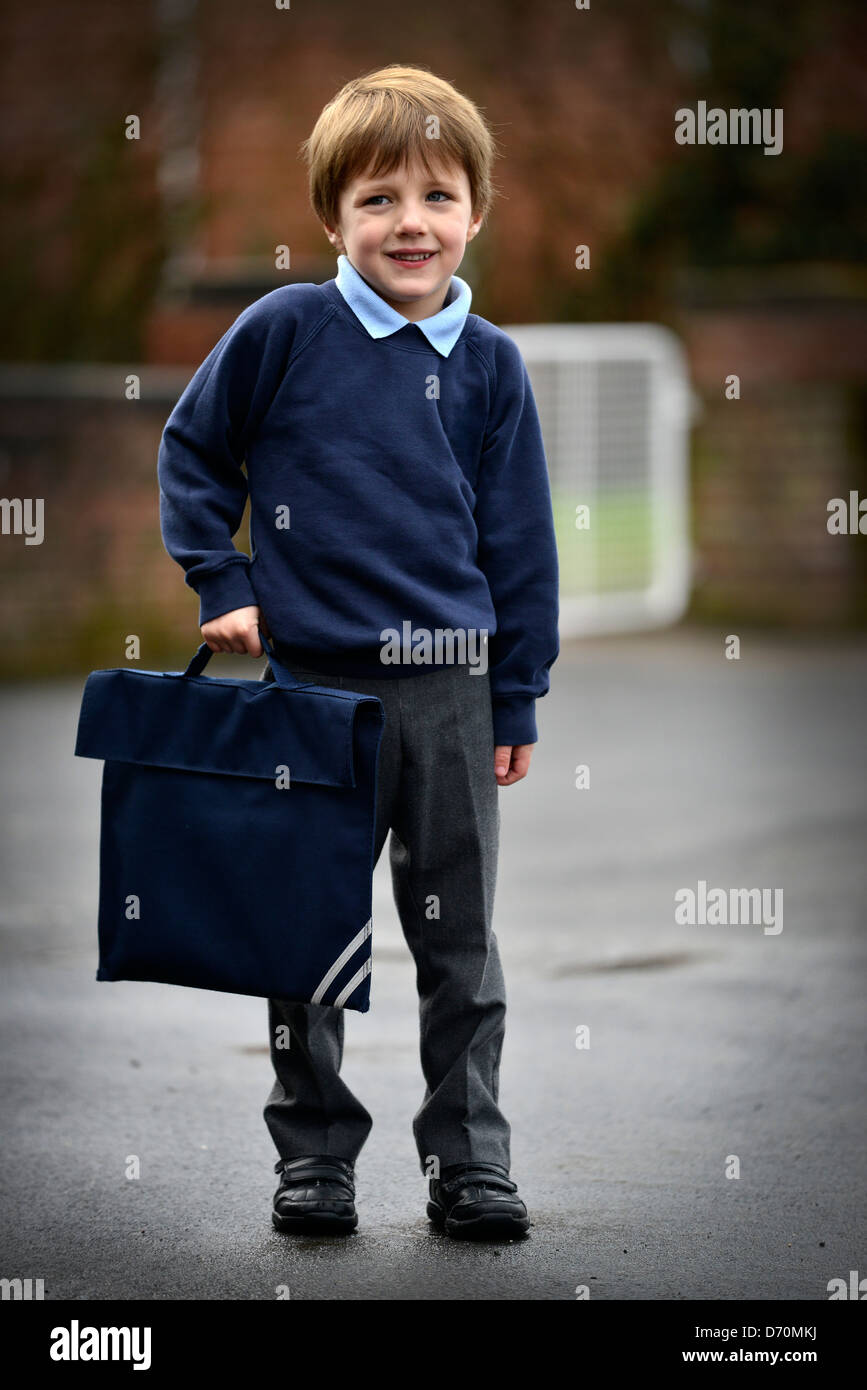 Un garçonnet de cinq ans portant son uniforme de l'école en dehors de l'école pour son premier jour. Banque D'Images