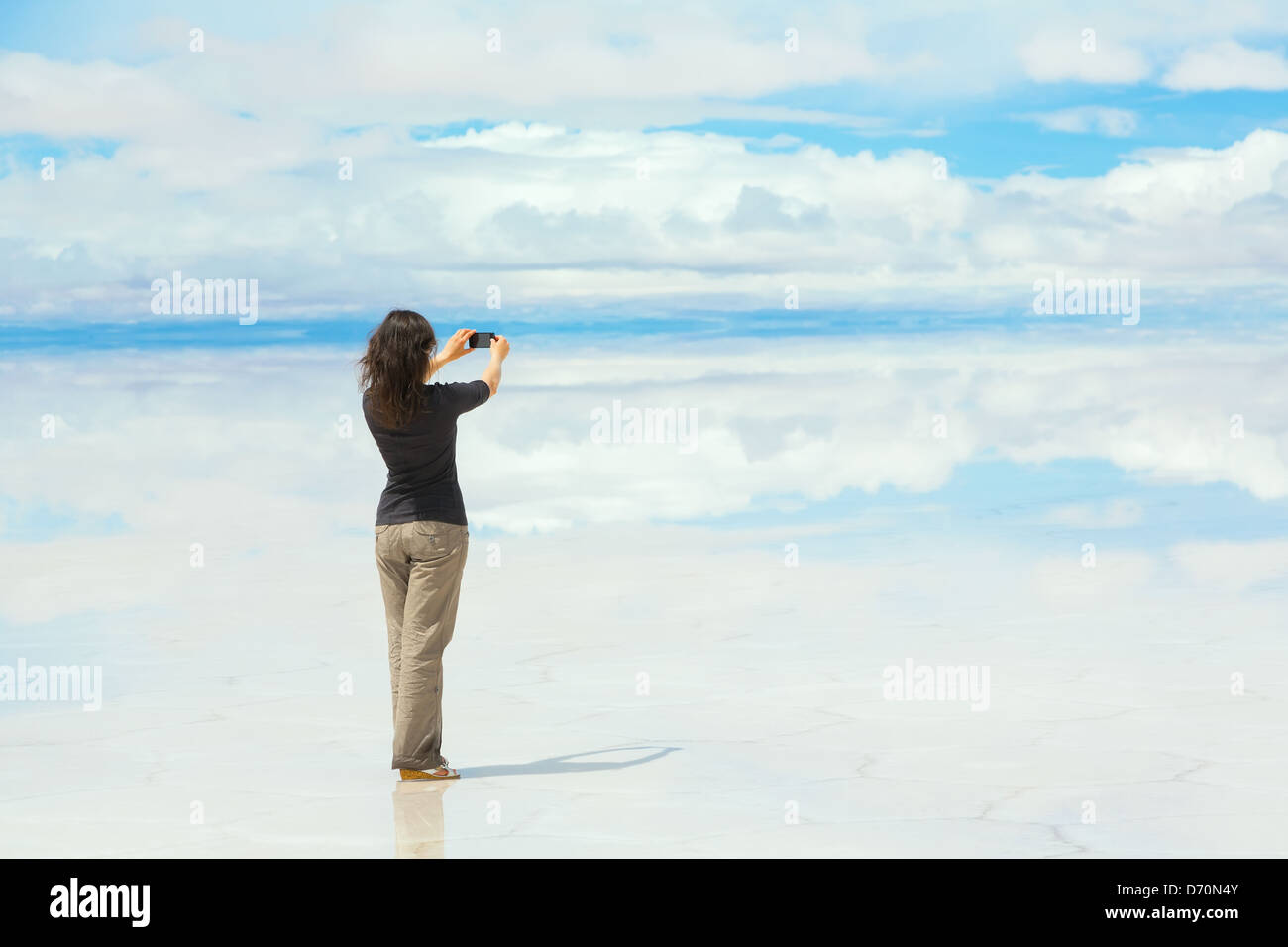 Girl Faire des photos sur un téléphone portable au milieu du lac Salar de Uyuni, Bolivie Banque D'Images