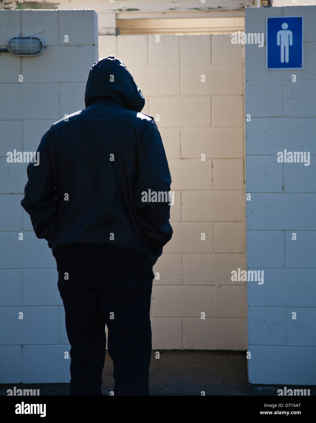 Un homme portant un sweat noir gents aller dans une toilette publique. Banque D'Images