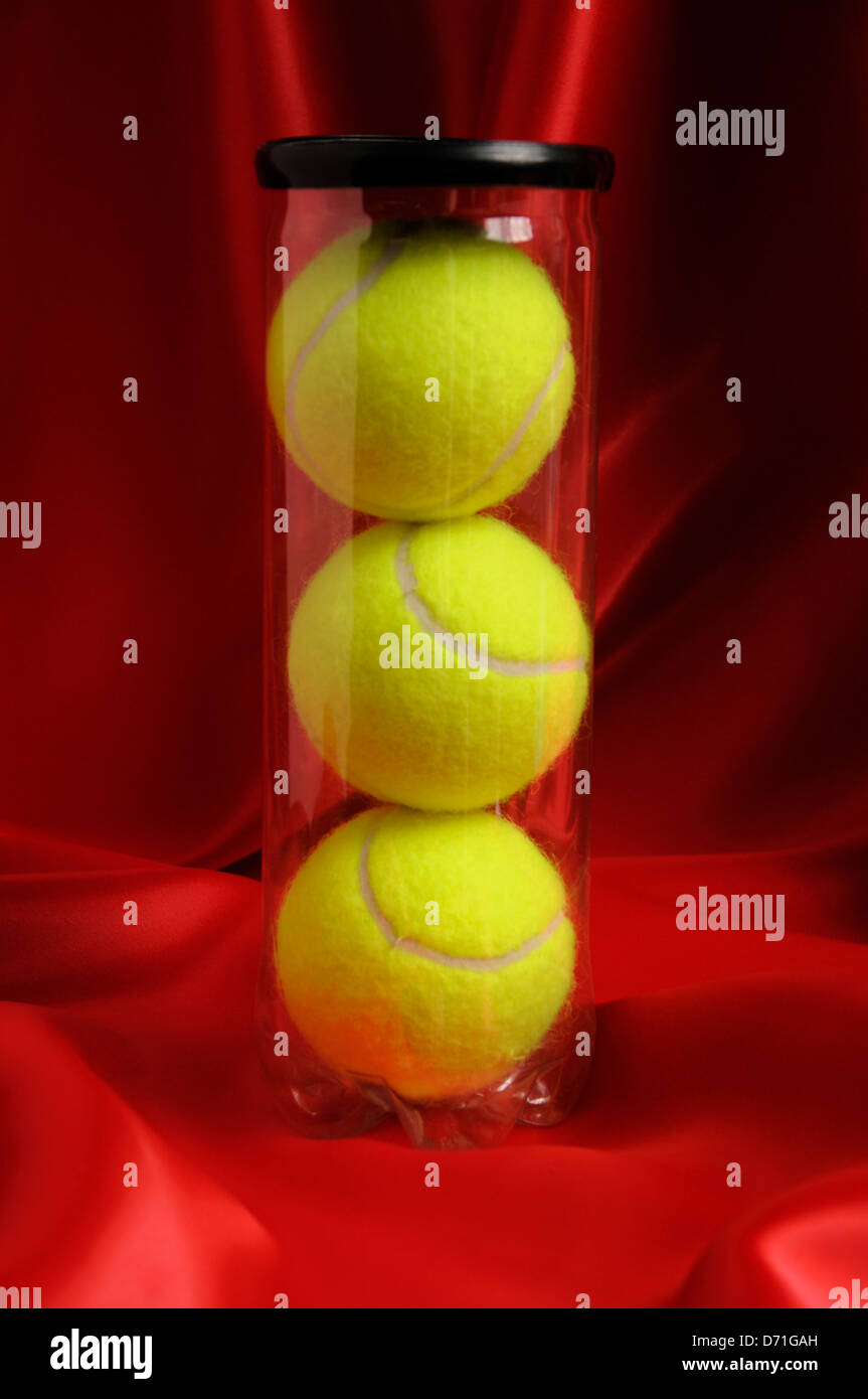 Les balles de tennis en boîte, sur fond de satin rouge. Banque D'Images