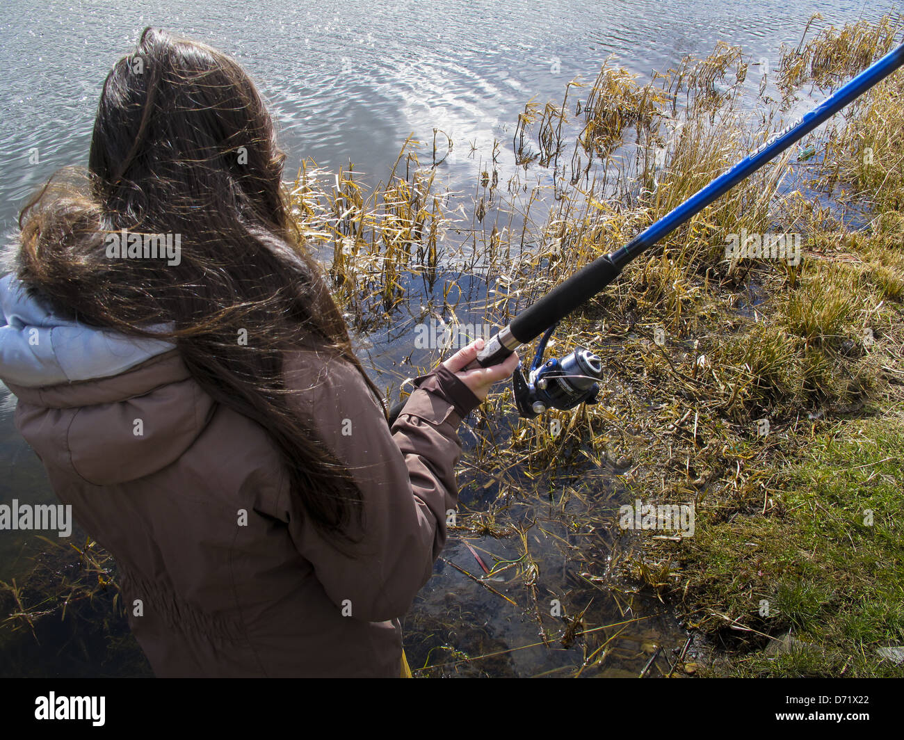 Jeune fille casting canne à pêche à côté canal Banque D'Images