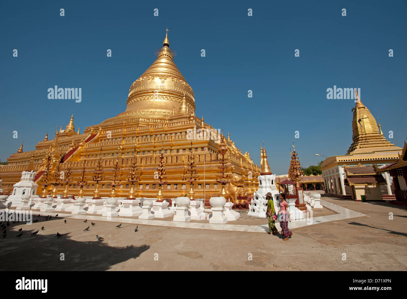 Deux femmes birmanes passent devant le grand dôme d'or de la Pagode Shwezigon Bagan Myanmar (Birmanie) Banque D'Images