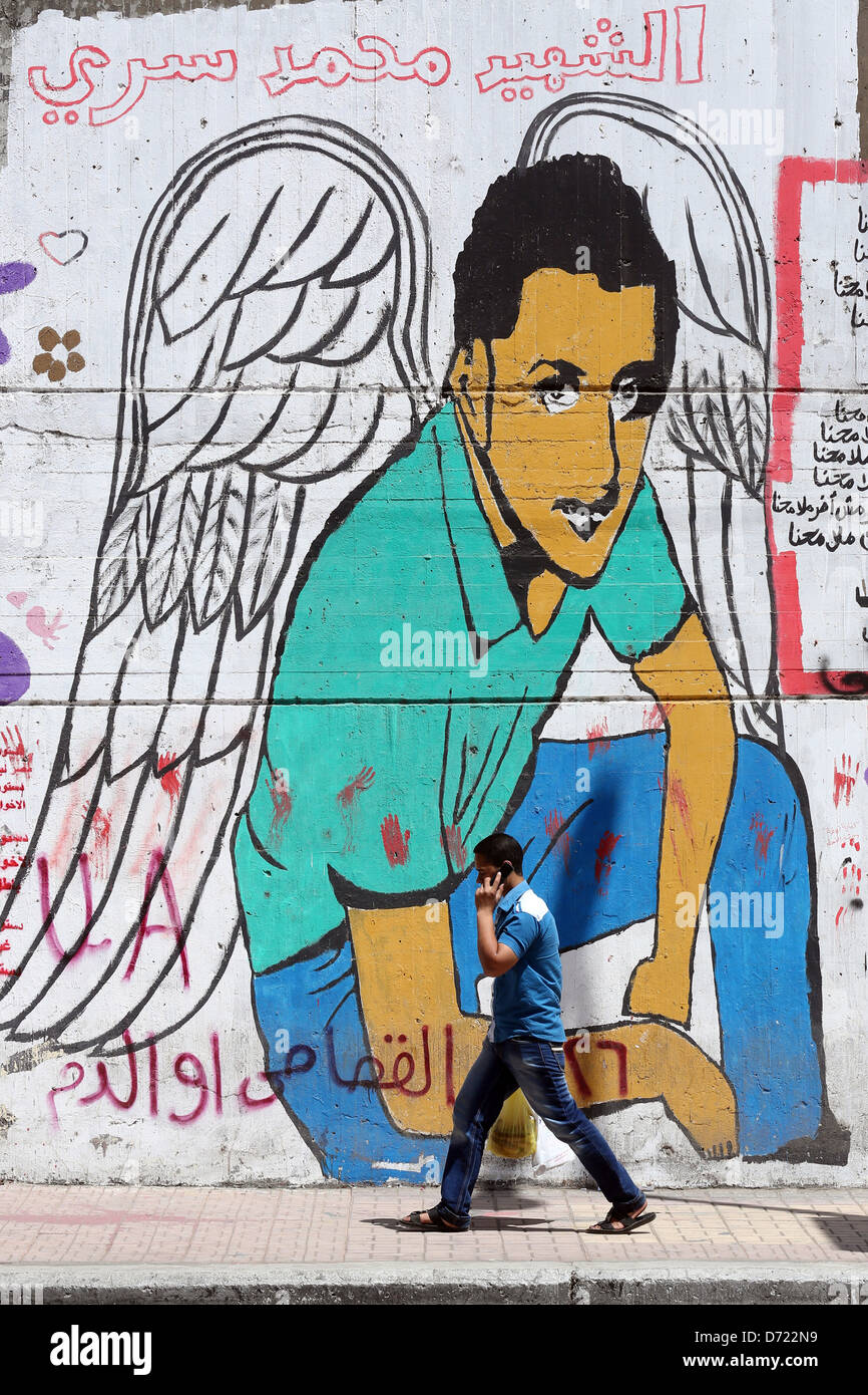 Homme marche devant une fresque révolutionnaire sur un mur des martyrs près de la place Tahrir au Caire. Banque D'Images