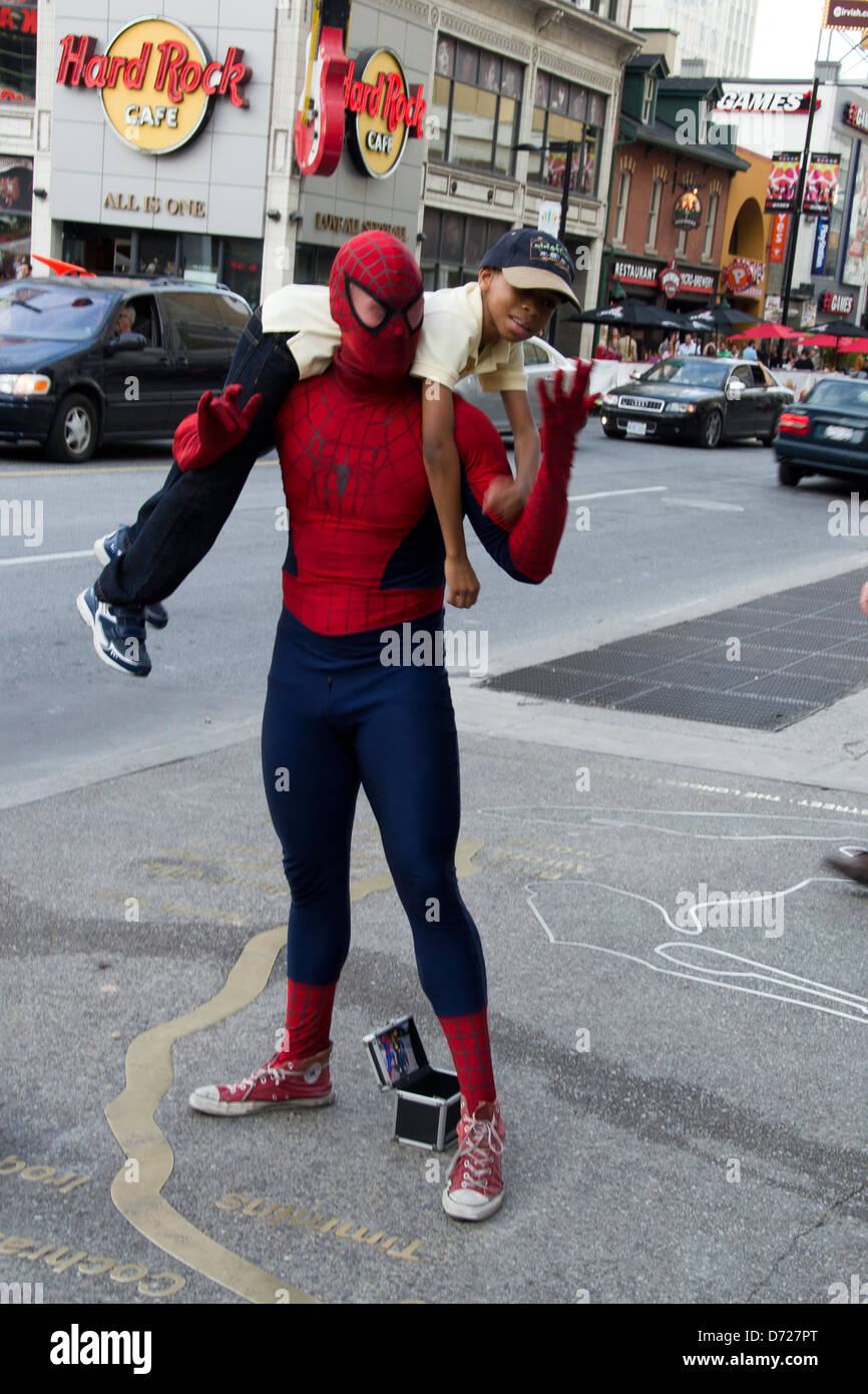 Un homme portant un masque de Spiderman portant un enfant sur son épaule. Banque D'Images