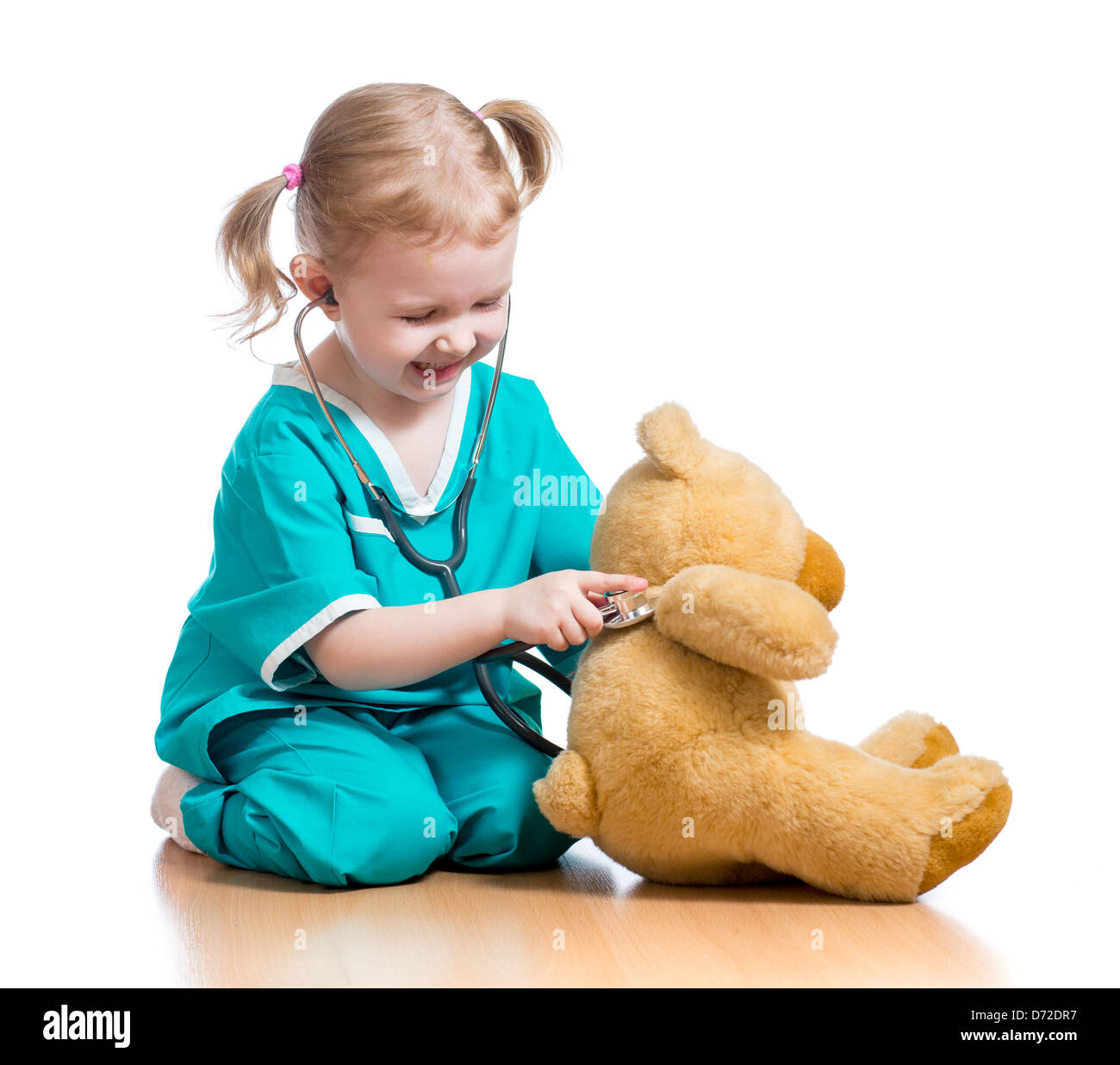 Adorable enfant avec des vêtements de médecin jouant avec peluche Banque D'Images