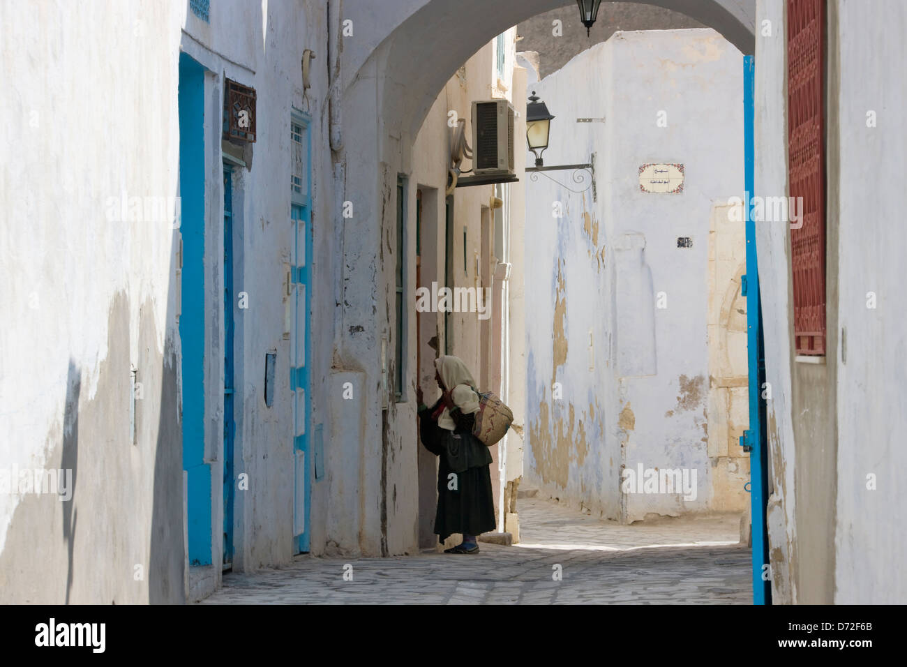 La femme de la rue bordée de maisons anciennes, Kairouan, Tunisie Banque D'Images