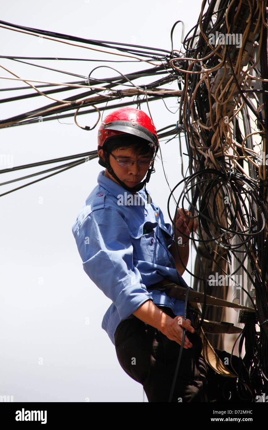 Ho Chi Minh Ville, Vietnam, Electrician repairing a câble pour une colonne d'alimentation Banque D'Images