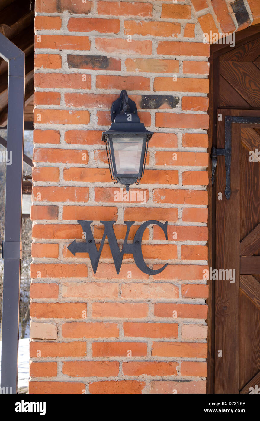 Wc toilettes signe symbole sur mur de brique rouge près de Retro eclairage. Banque D'Images