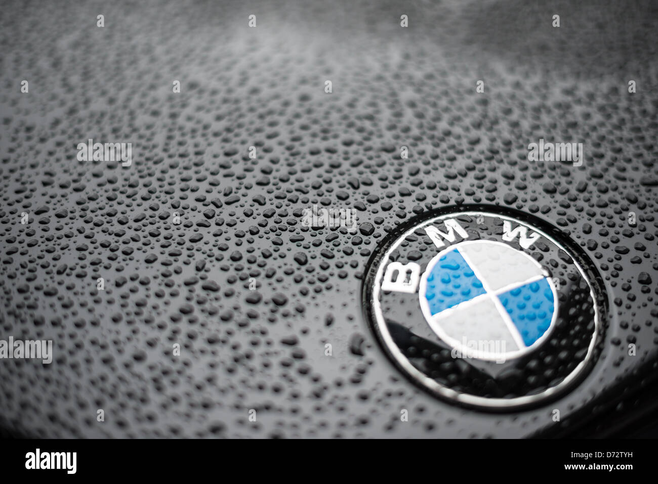 Gros plan d'un badge BMW sur le capot d'une voiture BMW noire, avec des gouttelettes d'eau formant de la pluie. Profondeur de champ. Banque D'Images