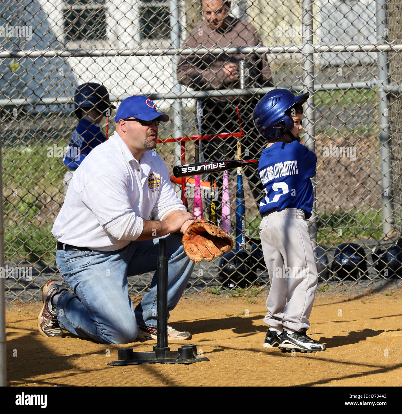 Peu tee ball t-ball joueur de baseball à la plaque avec son entraîneur. Banque D'Images