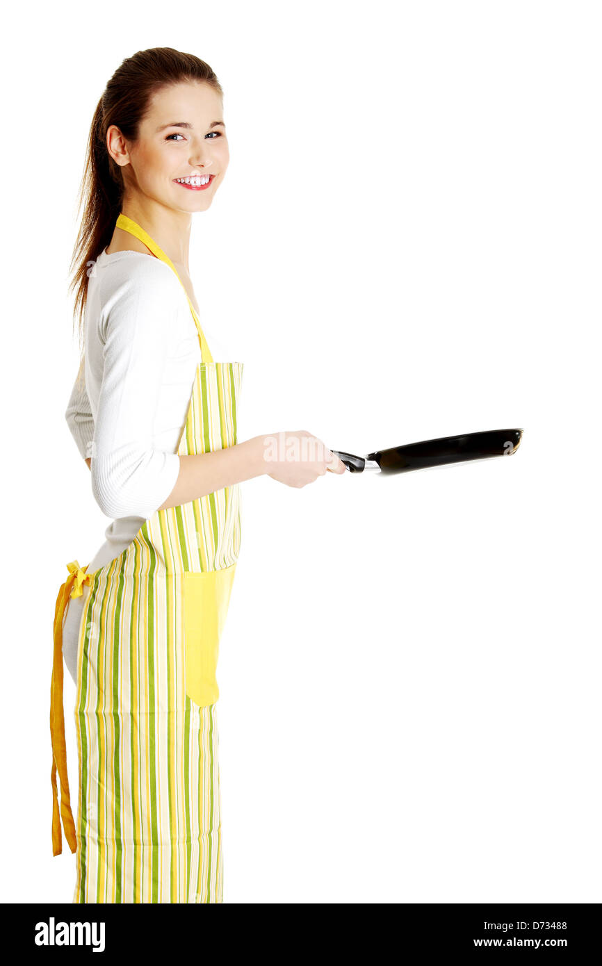 Young smiling caucasian girl dressed in apron, souriant derrière le poêle, isolé sur blanc. Banque D'Images