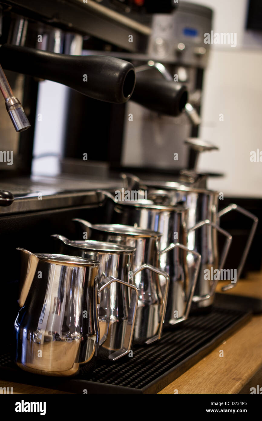 Une rangée de cinq bouteilles de lait en acier inoxydable afin de taille en face de machine à café Banque D'Images