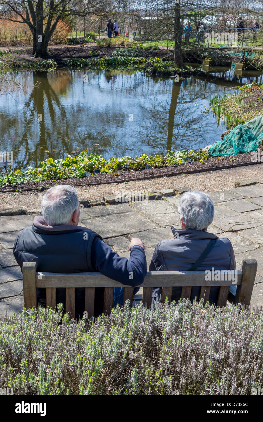 Couple de retraités âgés de vous détendre dans un jardin. RHS Hyde Hall Essex Banque D'Images