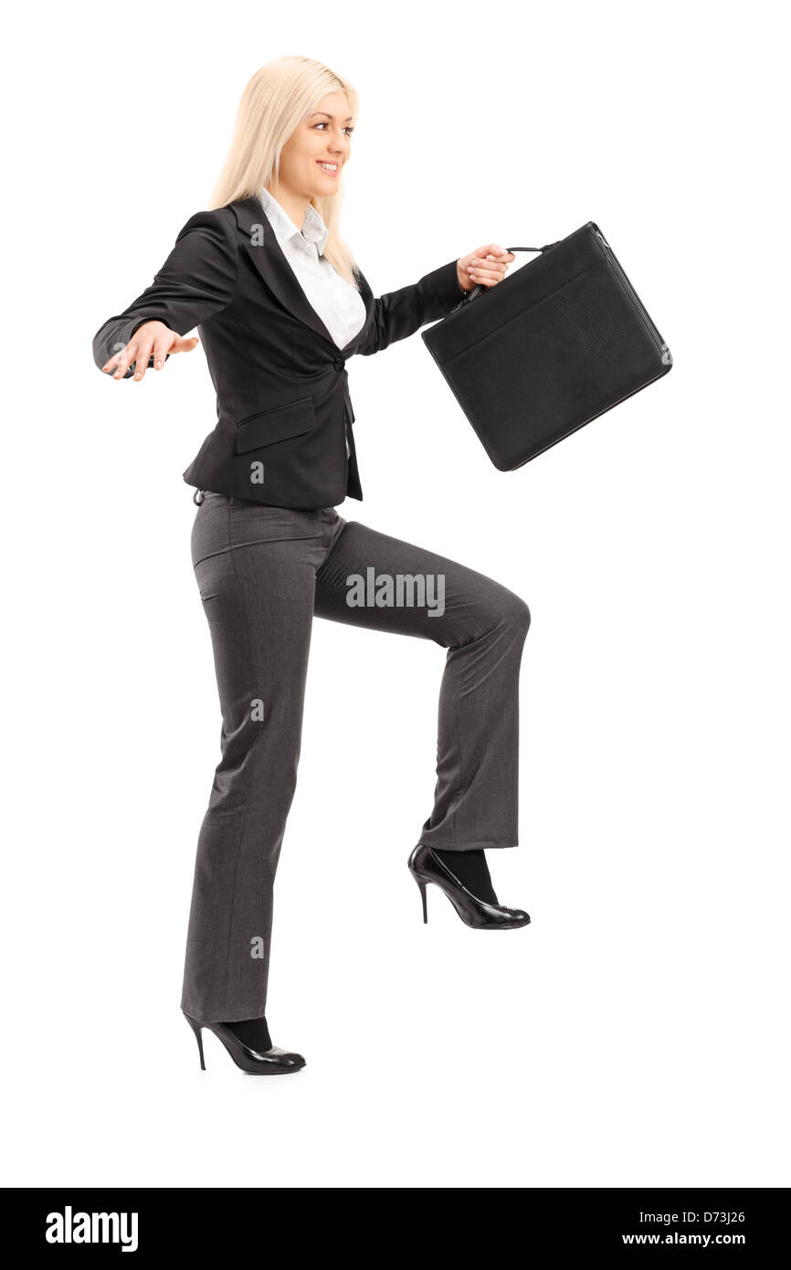 Full Length portrait of a businesswoman holding un porte-documents et en essayant de garder l'équilibre, isolé sur fond blanc Banque D'Images