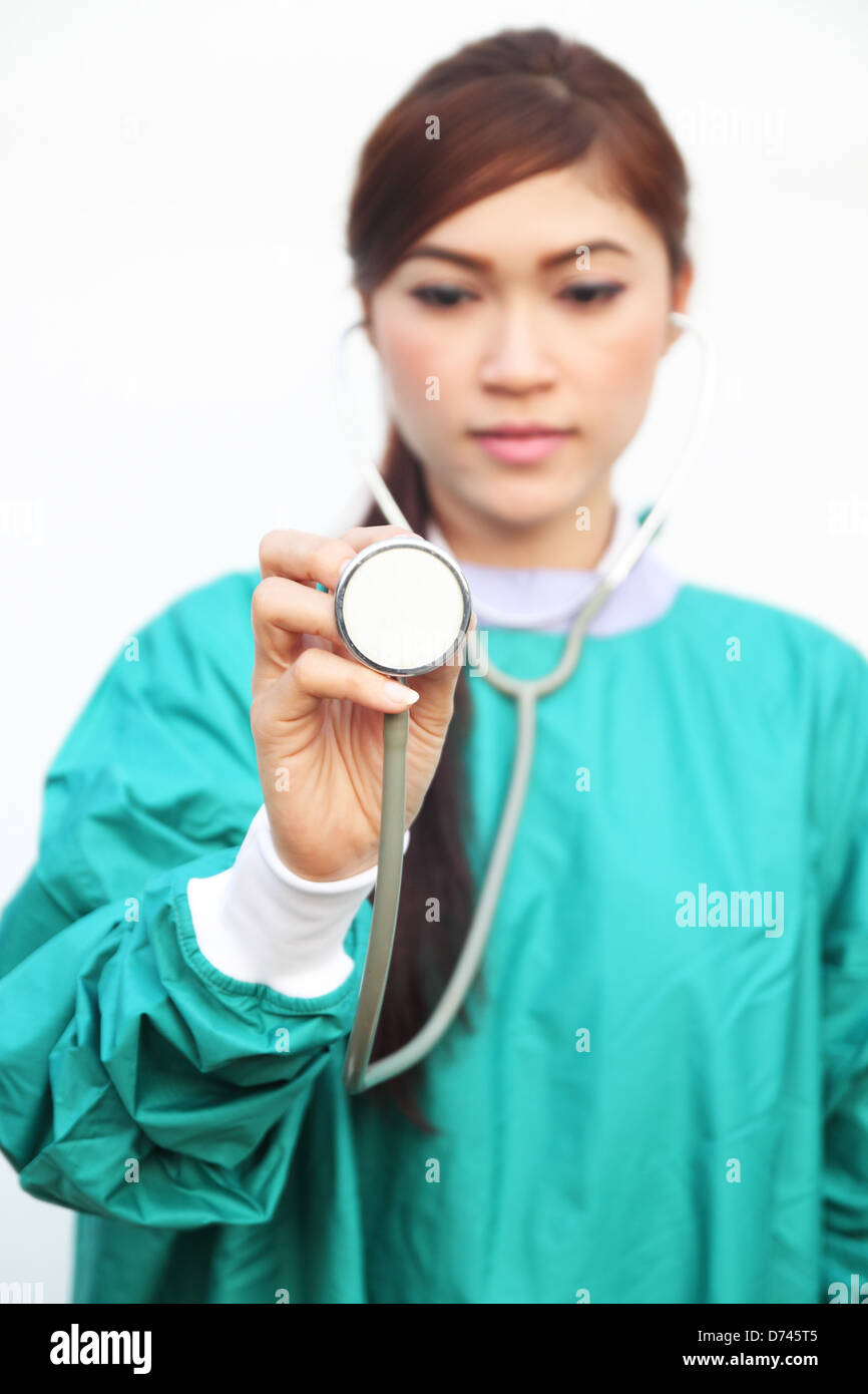 Femme médecin portant un stéthoscope et gommages vert sur fond blanc Banque D'Images